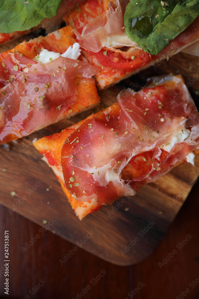 Pizza with parma ham salad rocket and parmesan on dark wooden background close up. Italian food
