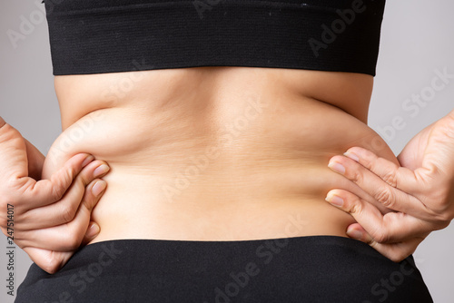 Fat woman hand holding excessive belly fat. Healthcare and woman diet lifestyle concept to reduce belly and shape up healthy stomach muscle. photo