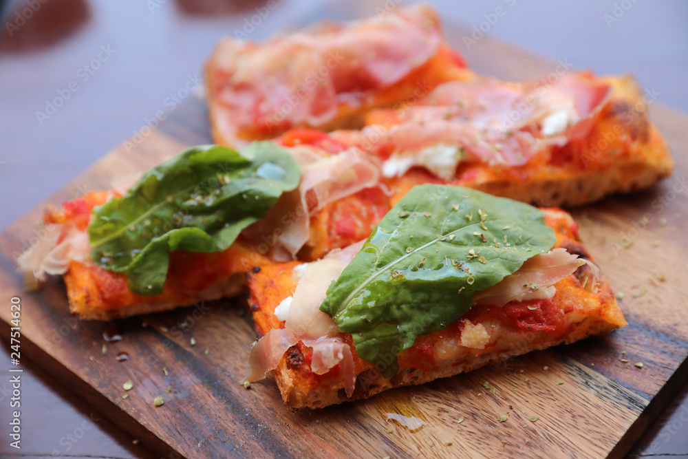 Pizza with parma ham salad rocket and parmesan on dark wooden background close up. Italian food Pizza with parma ham salad rocket and parmesan on dark wooden background close up. Italian food