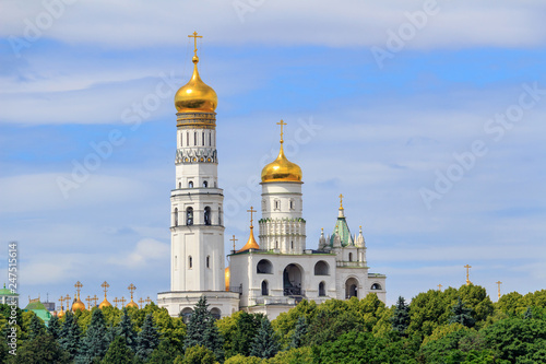 Ivan the Great Bell-Tower on territory of Moscow Kremlin against green trees and blue sky