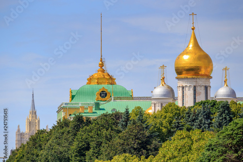 Domes of Cathedral of the Archangel on a background of Grand Kremlin Palace on territory of Moscow Kremlin against green trees and blue sky