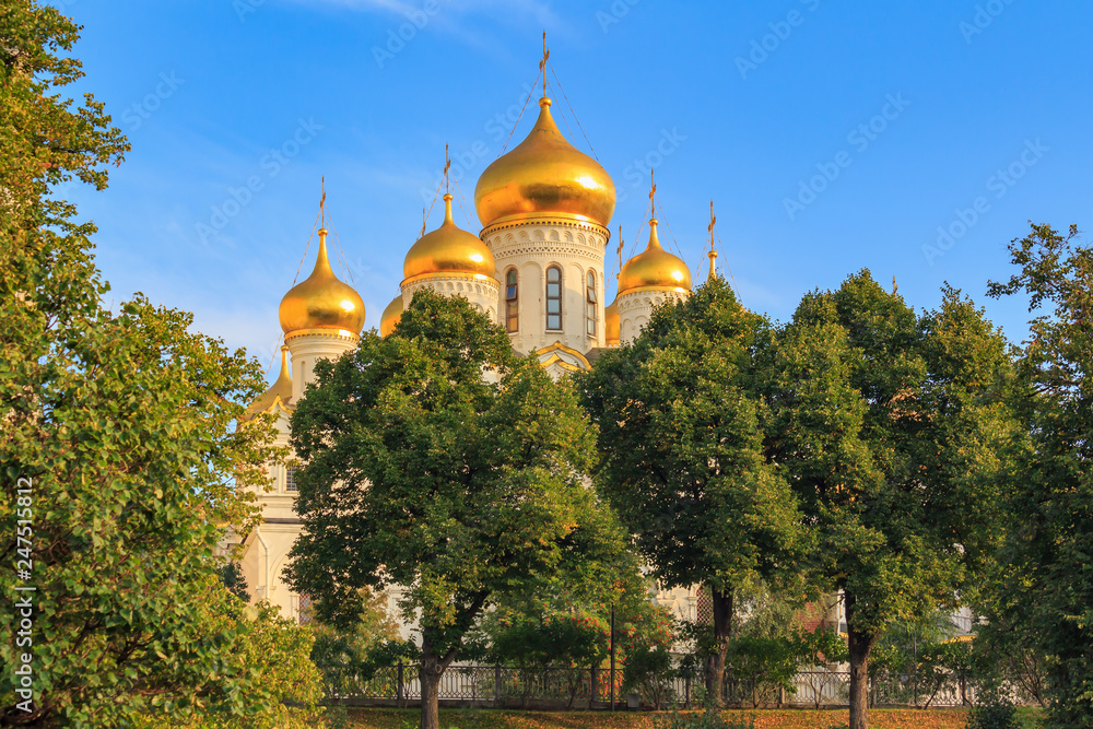 Cathedral of the Annunciation on Moscow Kremlin territory against blue sky and green trees in sunny early morning Cathedral of the Annunciation on Moscow Kremlin territory against blue sky and green trees in sunny early morning