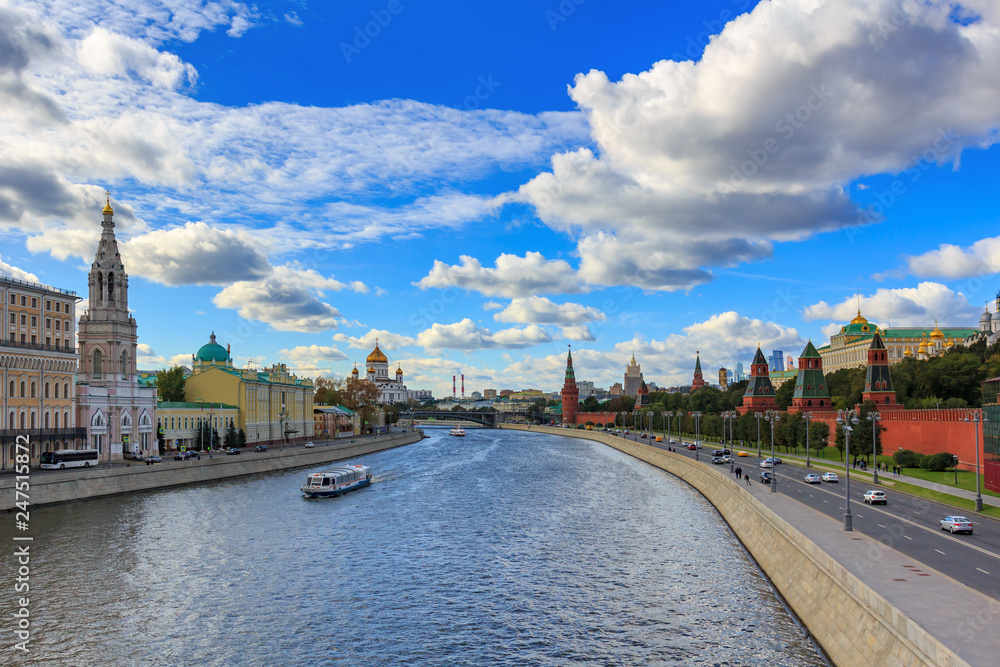 View of Moskva river and Kremlevskaya embankment in sunny day against blue sky with white clouds