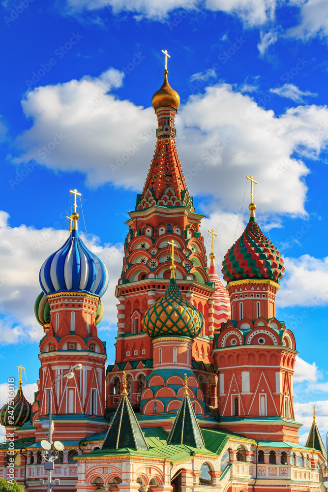 Architecture of St. Basil's Cathedral in sunny day on a background of blue sky with white clouds