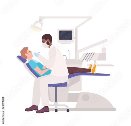 African American dentist examining male patient lying in chair