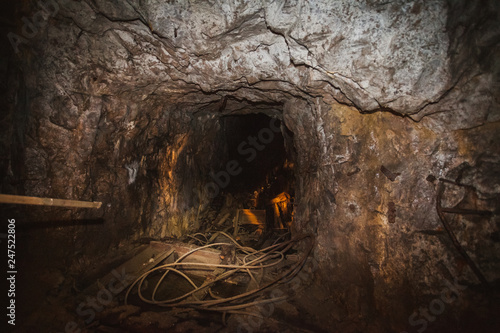 Inside old closed coal mine; dangerous tunnels full of dirt, lots of abandoned rusty equipment, devastated industrial place