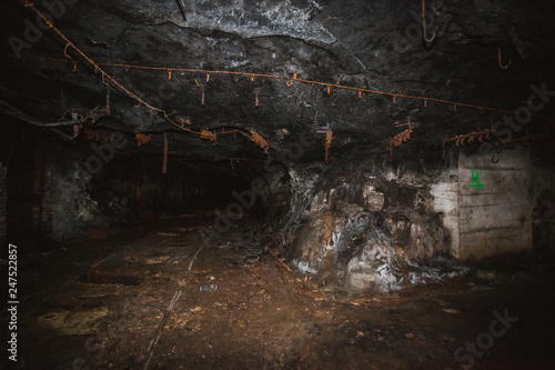 Inside old closed coal mine; dangerous tunnels full of dirt, lots of abandoned rusty equipment, devastated industrial place