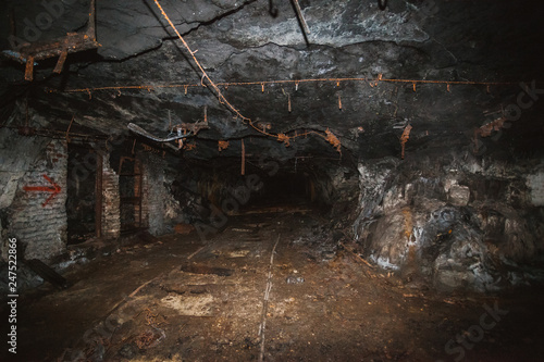 Inside old closed coal mine; dangerous tunnels full of dirt, lots of abandoned rusty equipment, devastated industrial place