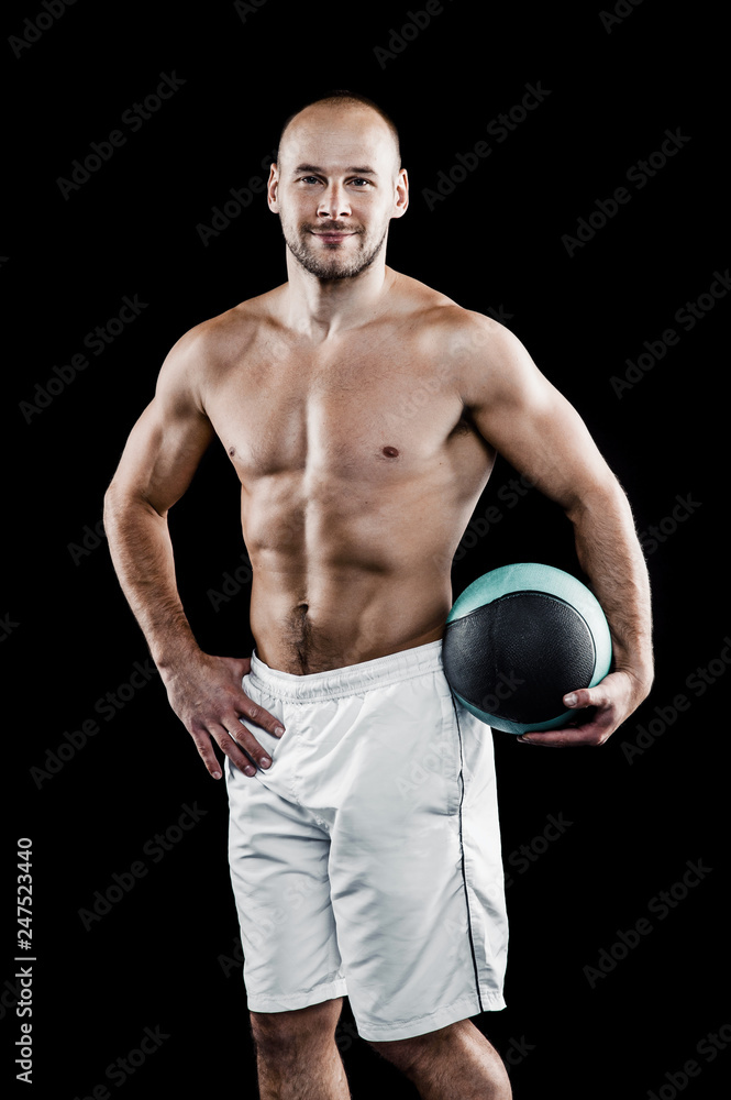 Spoptman working out with medicine ball, fitball fitness exercises. Copy space. Isolated on black background