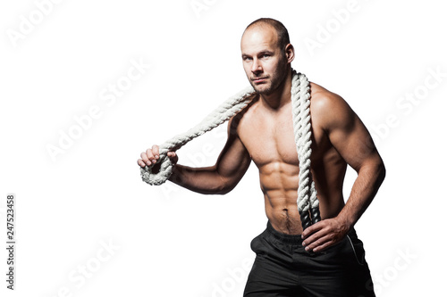 Young adult strong man holding rope around his neck. Posing in front of black background.