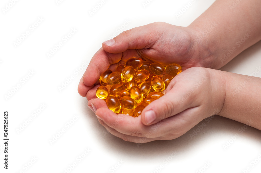 Children's hands hold the omega 3 capsules isolated on white background. The concept of health care and longevity. Children's hands hold the omega 3 capsules isolated on white background. The concept of health care and longevity.