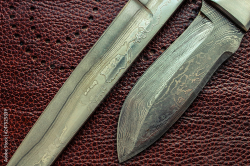 Damascus steel blades. Hunting knifes. Brown background. photo