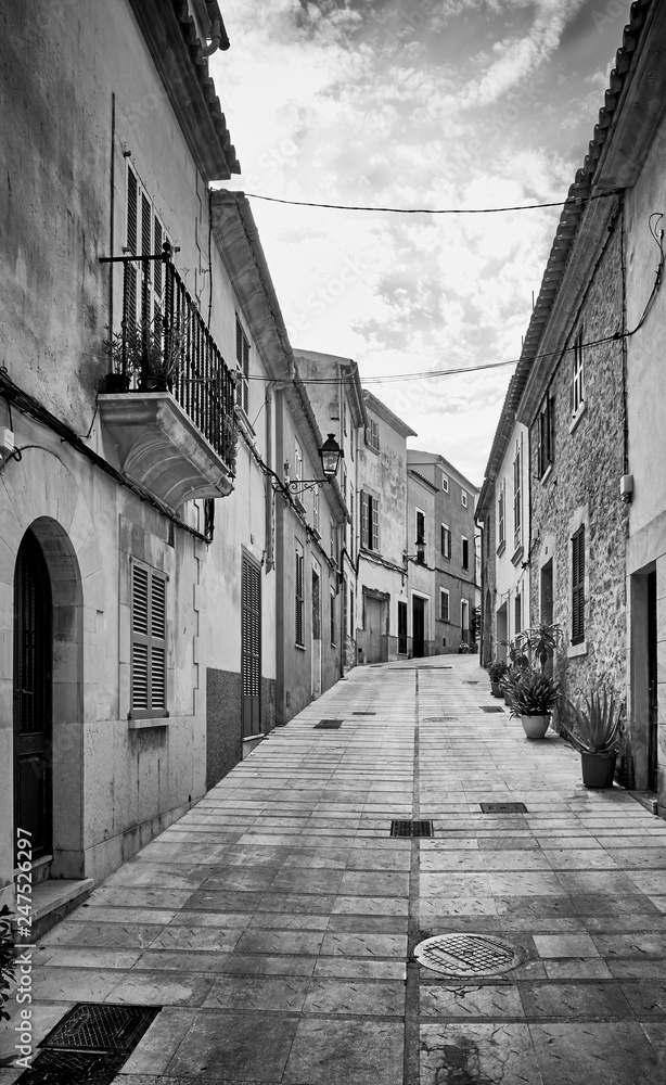 Black and white picture of a narrow steep street in Alcudia old town, Mallorca, Spain.