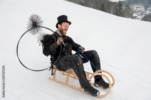 Schornsteinfeger auf Holzschlitten, Rutschpartie im Schnee photo