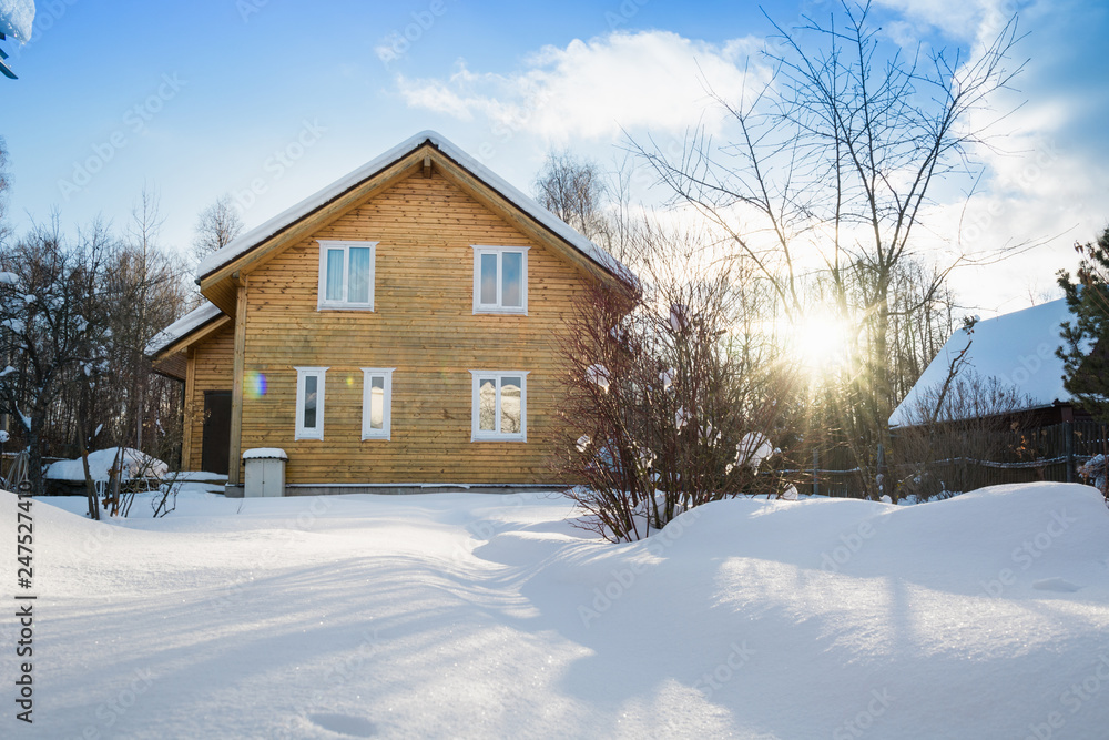 Wooden house in the russian countryside in winter. There is two-story house of timber. Frosty sunny day.