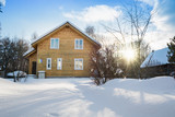Wooden house in the russian countryside in winter. There is two-story house of timber. Frosty sunny day.