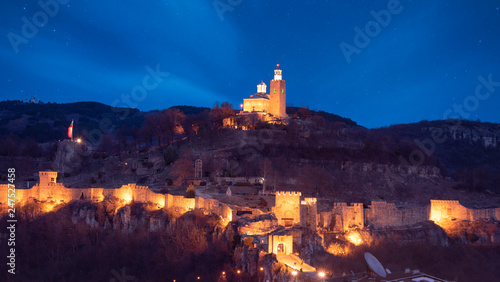 Beautiful panoramic view of illuminated medieval Tsarevets fortress in Veliko Tarnovo, Bulgaria at night. the famous historical capital. Panorama. Patriarch Church on the Tsarevets hill with lights photo