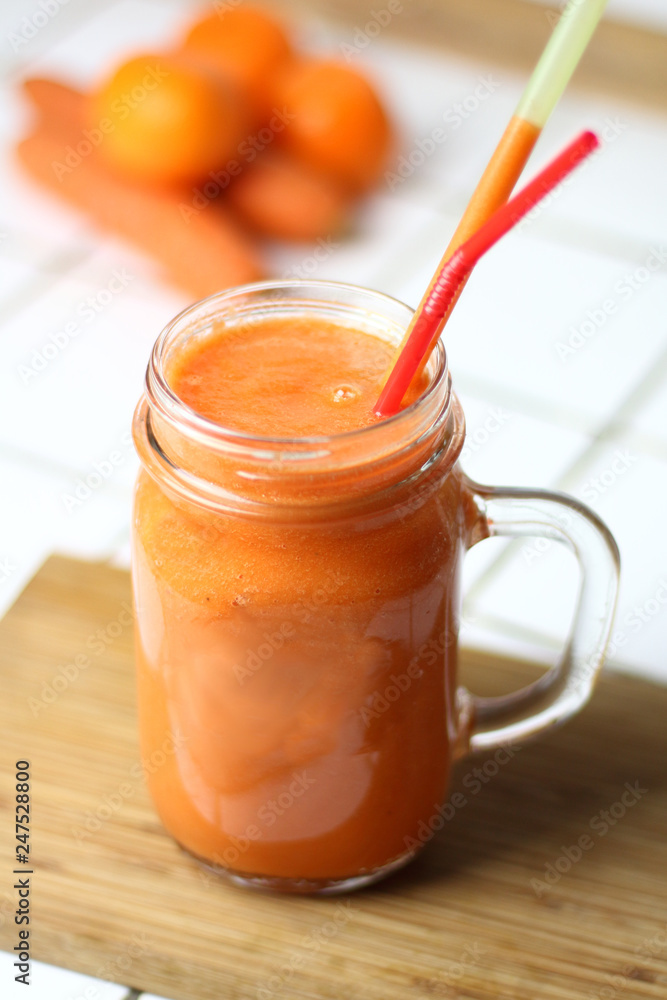 Orange healthy refreshing veggie carrot smoothie in a transparent glass with tubules on a white table by the day healthy nutrition diet detox Orange healthy refreshing veggie carrot smoothie in a transparent glass with tubules on a white table by the day healthy nutrition diet detox
