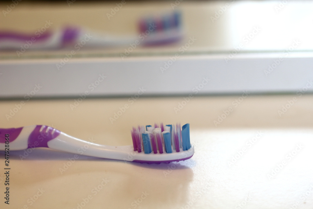 Pink toothbrush on the white shelf in the bathroom is reflected in the mirror , mornin care, tooth care and health Pink toothbrush on the white shelf in the bathroom is reflected in the mirror , mornin care, tooth care and health