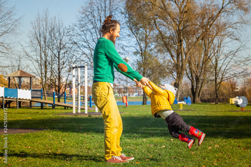 Fototapeta premium Father rotate infant son in public playground, Zagreb, Croatia.