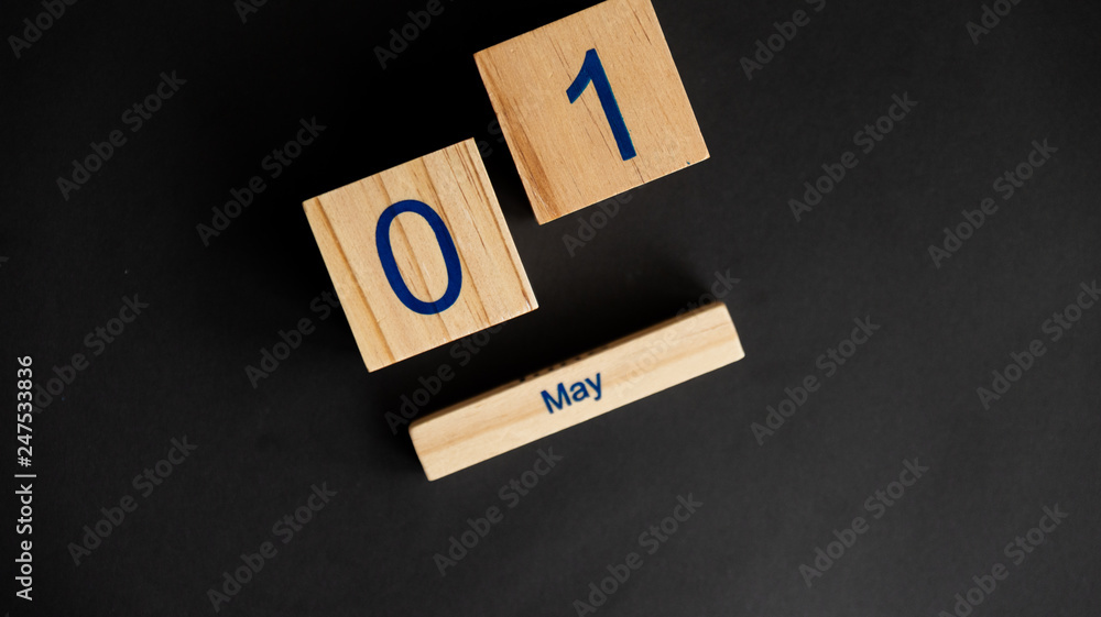 Three wooden cubes with figure of 1 of May. Concept of symbol of International Workers' Day and first day of May. Black studio background. Three wooden cubes with figure of 1 of May. Concept of symbol of International Workers' Day and first day of May. Black studio background.