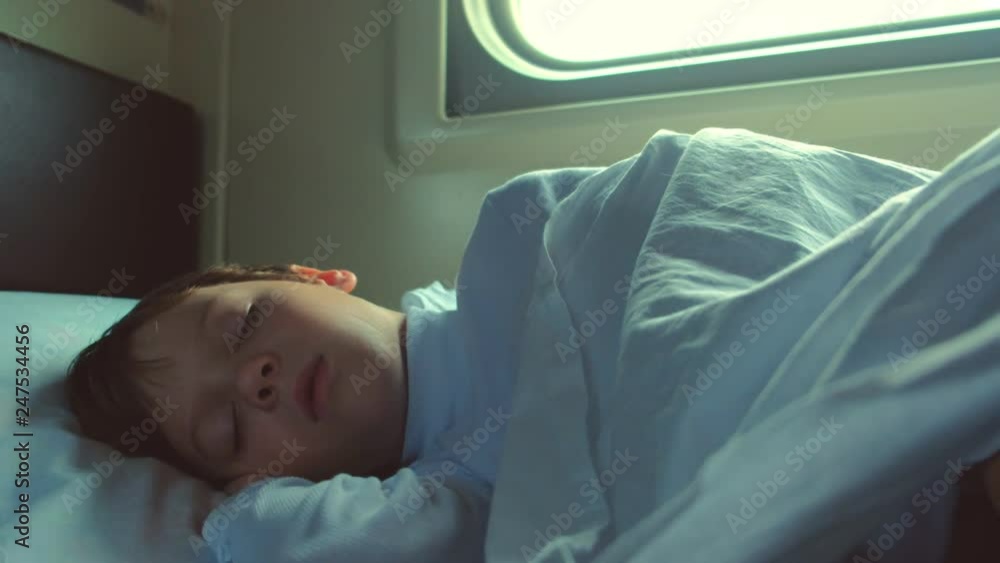 Boy is sleeping in the car of a moving train at early morning. Boy is sleeping in the car of a moving train at early morning.