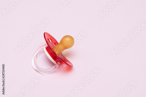 Baby new red pacifier on pink background.