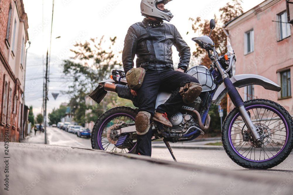 Obraz premium Handsome rider guy in helmet with off road enduro motorcycle at day time. Brutal urban lifestyle