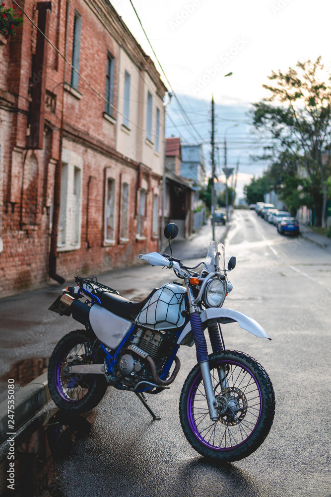 Vertical photo. Vintage old retro off road enduro motorcycle at day time. Brutal urban lifestyle