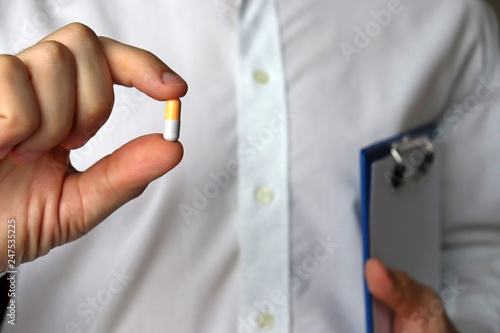 Doctor with pill, man holding capsule. Concept of medications, vitamins, cold and flu treatment, pharmacy