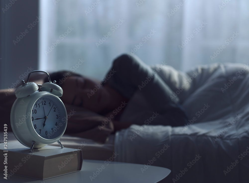 Woman sleeping in her bed and alarm clock - obrazy, fototapety, plakaty 