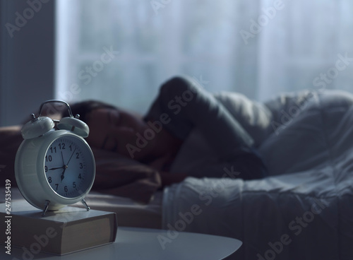 Woman sleeping in her bed and alarm clock