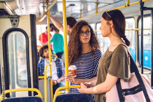 Two girls waiting in a bus to road up, standing and chatting.