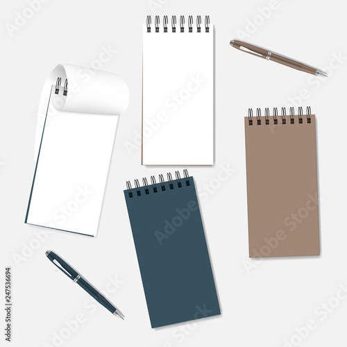 Spiral notebooks with white pages, colored covers and ballpoint pens