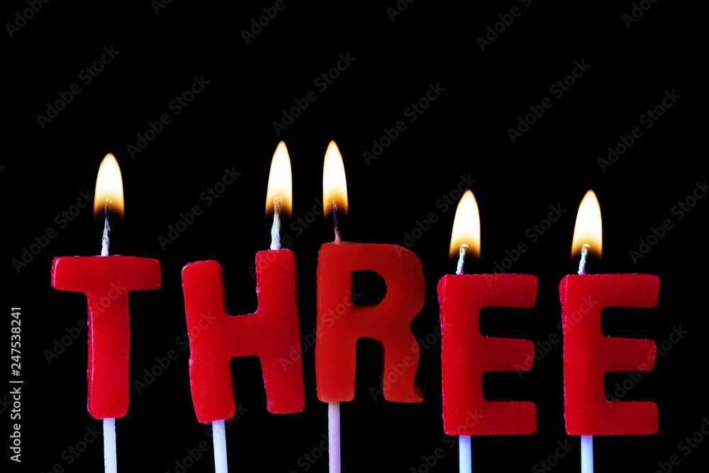 Three spellt out in red birthday candles against a black background Three spellt out in red birthday candles against a black background
