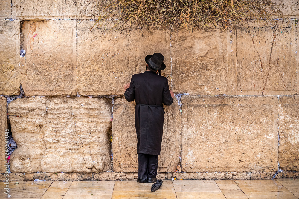 Believing Jew pray near the wall of crying in a big black hat