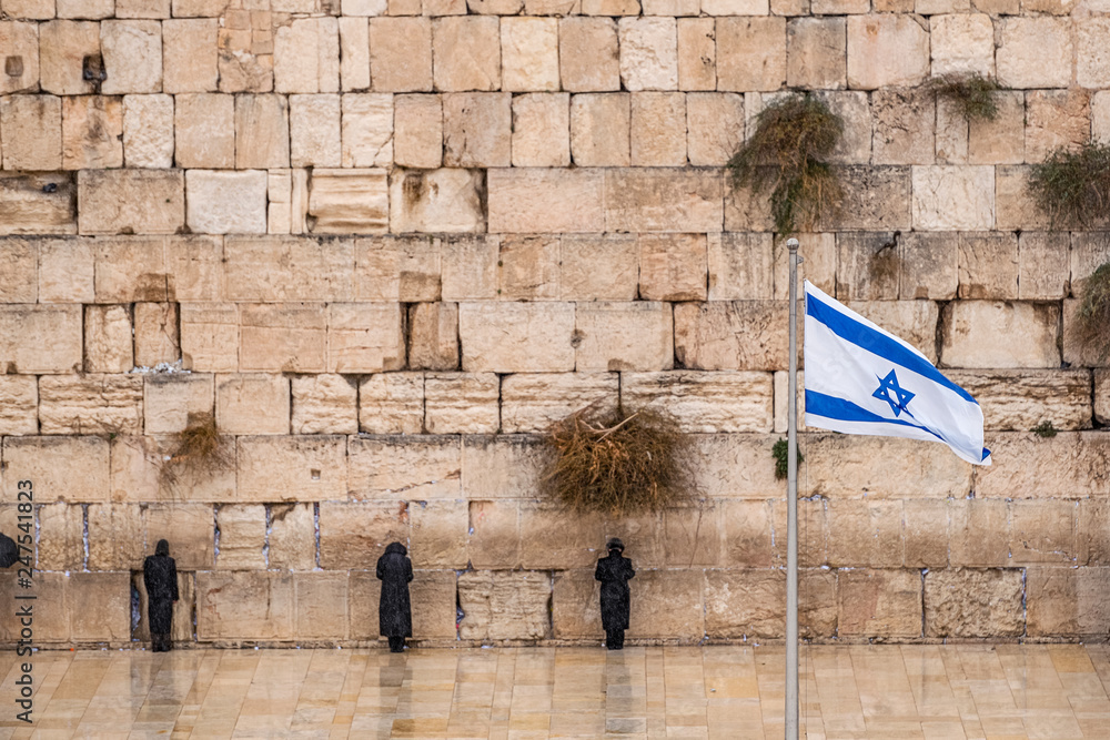 Israeli flag against the western wall on a cloudy day