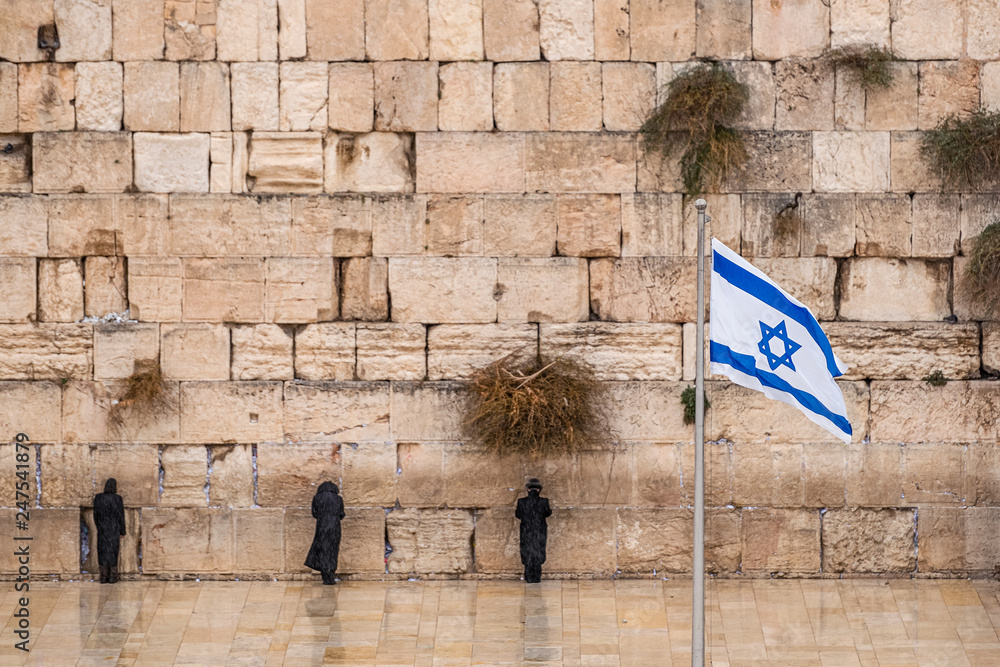 Israeli flag against the western wall on a cloudy day