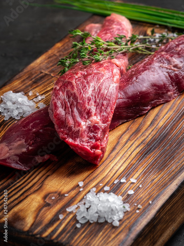 two steaks of juicy raw beef on a wooden  Board with salt and thyme photo