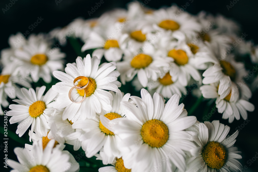 Obraz premium wedding rings on a bouquet of daisies
