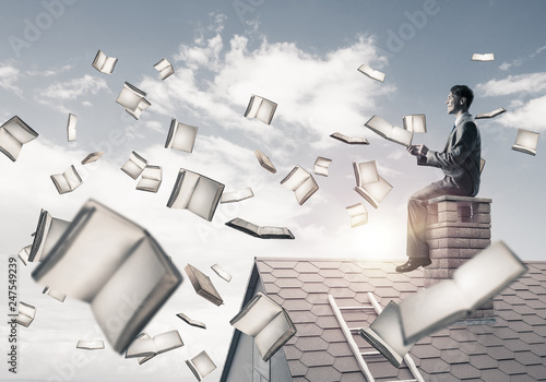 Man using smartphone and many books flying in air