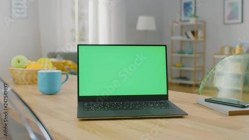 Wallpaper Mural Shot of a Modern Laptop with a Horizontal Green Screen Mock Up on a Wooden Table at Home. Smartphone Lies on a Table Next to the Computer. Torontodigital.ca