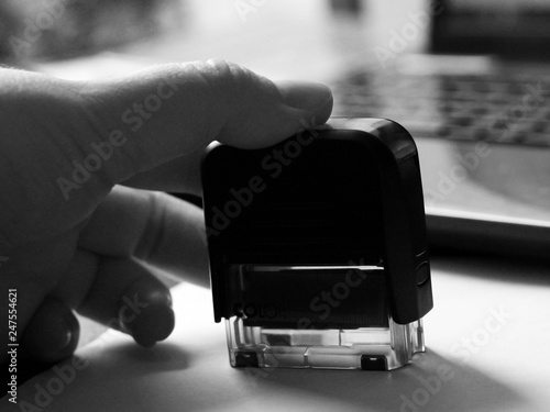 Hand puts a stamp on the document, black and white photo