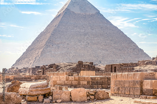 View of the incredibly majestic pyramid of the cheops on a sunny day in the desert with ancient ruins in the foreground