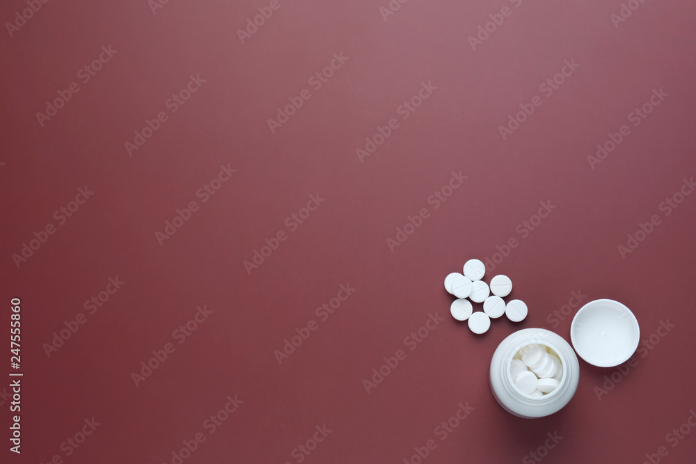 Medicines, supplements and drugs in a bottle on red background.The pill bottle medicine, photo isolated on red background. Flat lay. White pills. Copy space. Medicines, supplements and drugs in a bottle on red background.The pill bottle medicine, photo isolated on red background. Flat lay. White pills. Copy space.