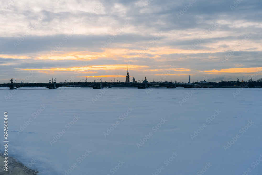 View at Peter-Pavel's Fortress in winter, frozen river in front, cloudy sunset sky, landscape view
