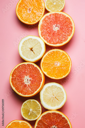 Beautifully sliced oranges, lemons, tangerines and other citruses on a pleasant pink background with copy space. Citrus frame for text
