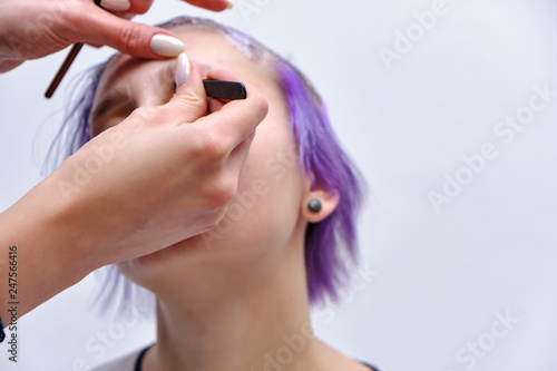 Beautiful girl with violet hair on white background master in make-up.