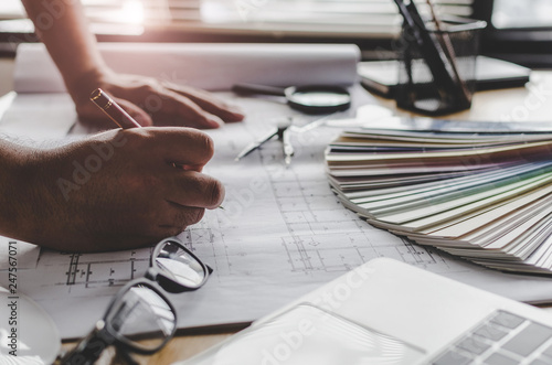 professional architect, engineer or interior drawing on blueprint with laptop and color palette on workplace desk in office center at construction site, contractor, construction, engineering concept