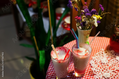 milk berries cocktails on a cheсkered table cloth with flowers in a vase
